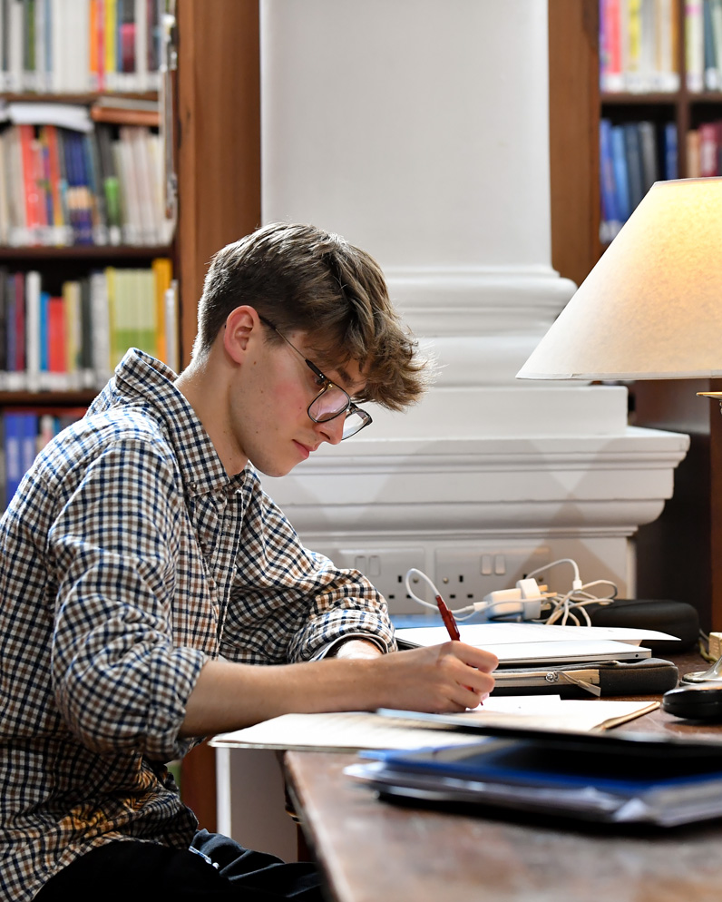 A large audience seated closely together in a bright event hall, smiling.